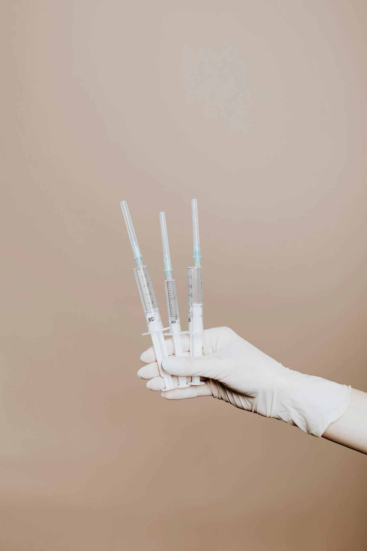 Person Holding Three Syringes with Medicine<br />
